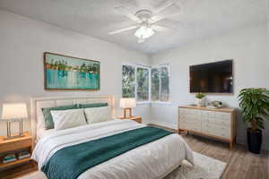 Bedroom featuring a textured ceiling, light wood-type flooring, and ceiling fan