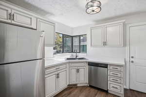 Kitchen featuring a textured ceiling, appliances with stainless steel finishes, sink, and dark hardwood / wood-style floors