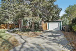 View of property hidden behind natural elements with a garage