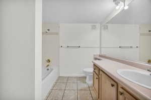 Full bathroom with vanity, toilet, tile patterned flooring, and tiled shower / bath