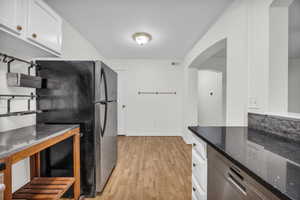 Kitchen with stainless steel finishes, white cabinets, granite countertop.