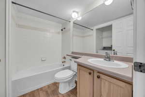 Full bathroom featuring toilet, tiled shower / bath, vanity, and wood-type flooring