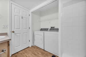 Laundry area featuring washing machine and dryer and light wood-type flooring