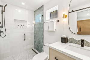 Bathroom featuring toilet, walk in shower, and vanity