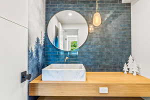 Bathroom featuring tile walls, vanity, and decorative backsplash