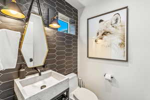 Bathroom featuring tile walls, vanity, and toilet