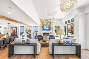 Living room with a chandelier, light hardwood / wood-style flooring, and a stone fireplace