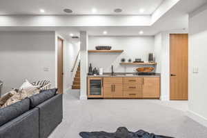 Kitchen featuring sink, light brown cabinets, light carpet, and beverage cooler