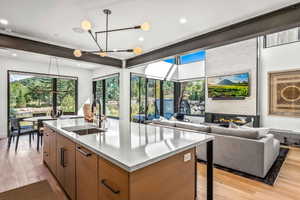 Kitchen featuring sink, light hardwood / wood-style floors, pendant lighting, a breakfast bar area, and a kitchen island with sink