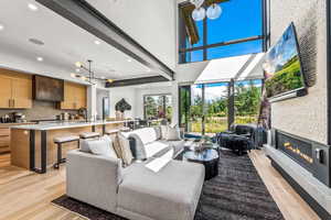 Living room with beamed ceiling, sink, light hardwood / wood-style flooring, and a towering ceiling