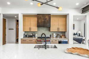 Kitchen with appliances with stainless steel finishes, decorative backsplash, light brown cabinetry, and range hood