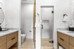 Bathroom with vanity, tile patterned floors, toilet, and walk in shower