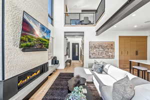 Living room with light hardwood / wood-style flooring and a high ceiling