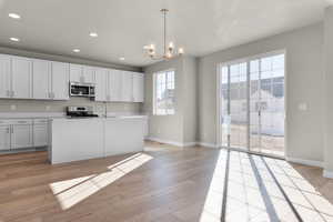 Kitchen featuring pendant lighting, stainless steel appliances, a wealth of natural light, and a notable chandelier