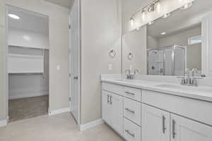 Bathroom with tile patterned floors, vanity, and a shower with door