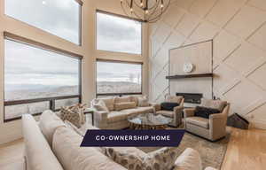 Living room featuring a large fireplace, a chandelier, wood-type flooring, a towering ceiling, and a mountain view