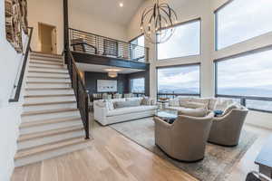 Living room featuring a water and mountain view, a high ceiling, a notable chandelier, and light wood-type flooring