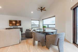 Dining space featuring ceiling fan, high vaulted ceiling, light wood-type flooring, and plenty of natural light