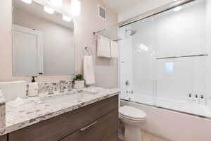 Full bathroom featuring vanity, toilet, and combined bath / shower with glass door