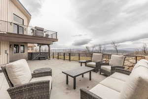 View of patio / terrace featuring a hot tub, a mountain view, outdoor lounge area, and a balcony