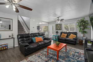 Living room featuring dark wood-type flooring, a textured ceiling, and ceiling fan