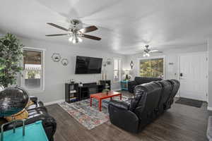 Living room with ceiling fan, a textured ceiling, and dark hardwood / wood-style floors