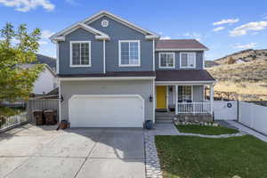 Front facade featuring a front yard, a garage, a mountain view, and a porch