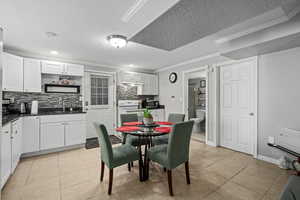 Tiled dining area with ornamental molding, a textured ceiling, and sink