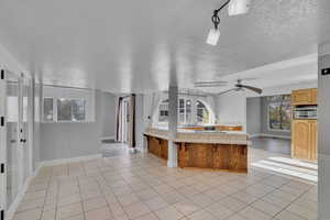 Kitchen with ceiling fan, a textured ceiling, rail lighting, and light tile patterned floors