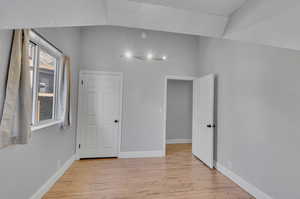 Spare room with vaulted ceiling and light hardwood / wood-style floors