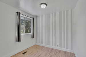 Unfurnished room with a textured ceiling and light hardwood / wood-style flooring