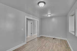 Unfurnished room with light hardwood / wood-style flooring and a textured ceiling