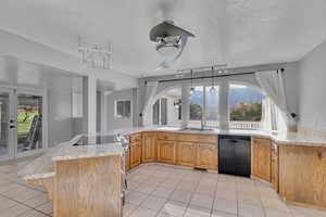 Kitchen with black dishwasher, stainless steel range with electric stovetop, hanging light fixtures, kitchen peninsula, and a textured ceiling