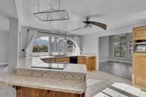 Kitchen featuring kitchen peninsula, ceiling fan, a textured ceiling, light hardwood / wood-style flooring, and black appliances