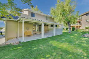 Back of property featuring a patio area, a yard, and ceiling fan