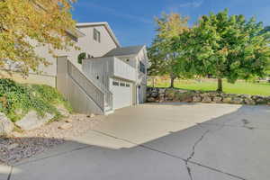 View of side of property with a garage, a lawn, and a balcony