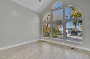 Empty room with light hardwood / wood-style floors, high vaulted ceiling, and ceiling fan