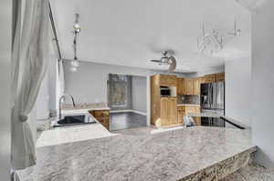 Kitchen featuring kitchen peninsula, sink, decorative light fixtures, appliances with stainless steel finishes, and ceiling fan