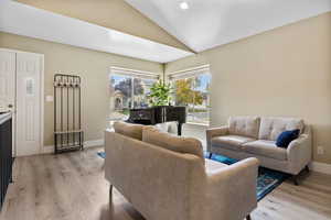 Living room featuring vaulted ceiling and light hardwood / wood-style flooring