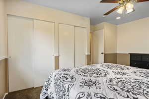 Carpeted bedroom with multiple closets and ceiling fan