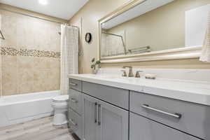 Full bathroom featuring vanity, shower / bath combo, hardwood / wood-style flooring, and toilet