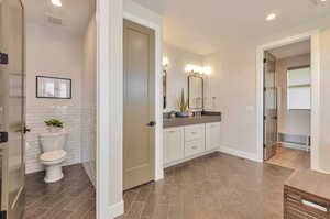 Bathroom with tile walls, vanity, and toilet