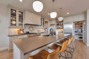 Kitchen featuring a breakfast bar, a kitchen island with sink, sink, and light wood-type flooring