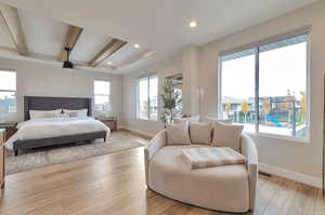 Primary Bedroom with light hardwood / wood-style floors and beam ceiling and sitting room