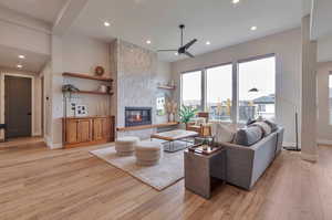 Living room featuring light hardwood / wood-style floors, a tiled fireplace, and ceiling fan