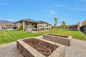 Rear view of house with a mountain view, a trampoline, a patio, and a lawn