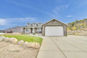 View of front of home with a front yard, a garage, a mountain view, and a porch