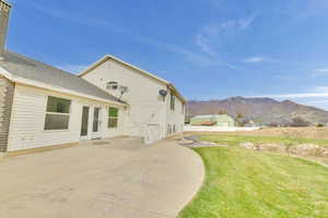 Back of property featuring a patio, a mountain view, and a lawn