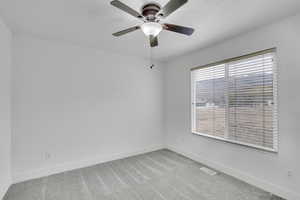 Carpeted empty room featuring ceiling fan