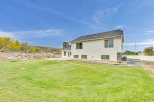 Rear view of house featuring central air condition unit, a patio, and a lawn